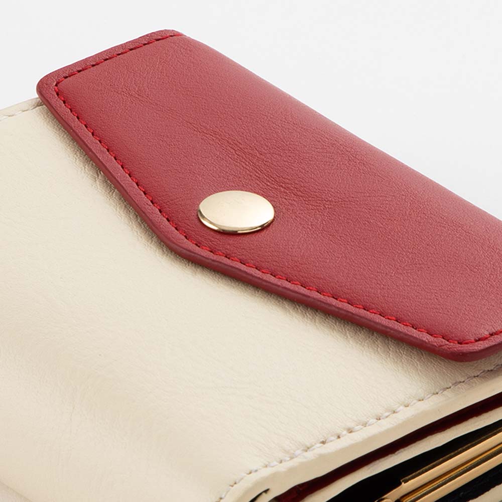 がま口２つ折り財布 - 鞄の中で開かないように、強めのホックを使用しています。負荷のかかりやすいフラップに厚めの芯材が入ることによって、開けやすさとヘタリにくさを両立しています。