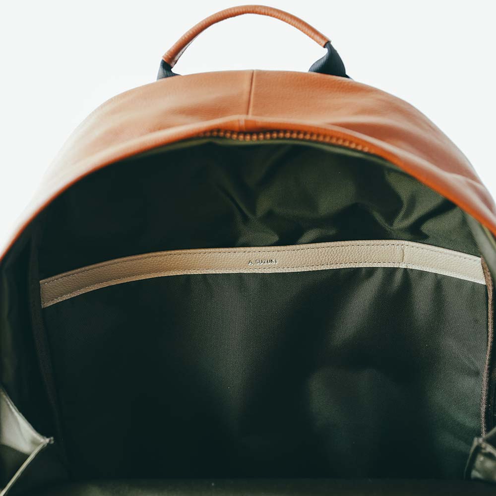 ラウンドレザーバックパック - 名入れは背中側の内側ポケットのレザー部分に入ります。無料の刻印オプションで、世界で1つだけの特別なアイテムに。