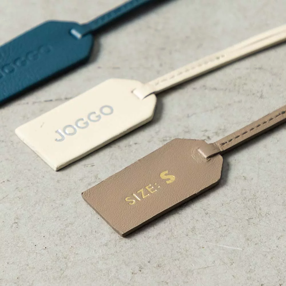 レザートングサンダルＬ（26.5-28cm） - 付属しているブランドタグの片面にＪＯＧＧＯロゴ、もう片面にサイズを刻印しています。タグの色は鼻緒と同じ色になります。※ロゴ刻印をなしにするとサイズのみ刻印された状態になります。