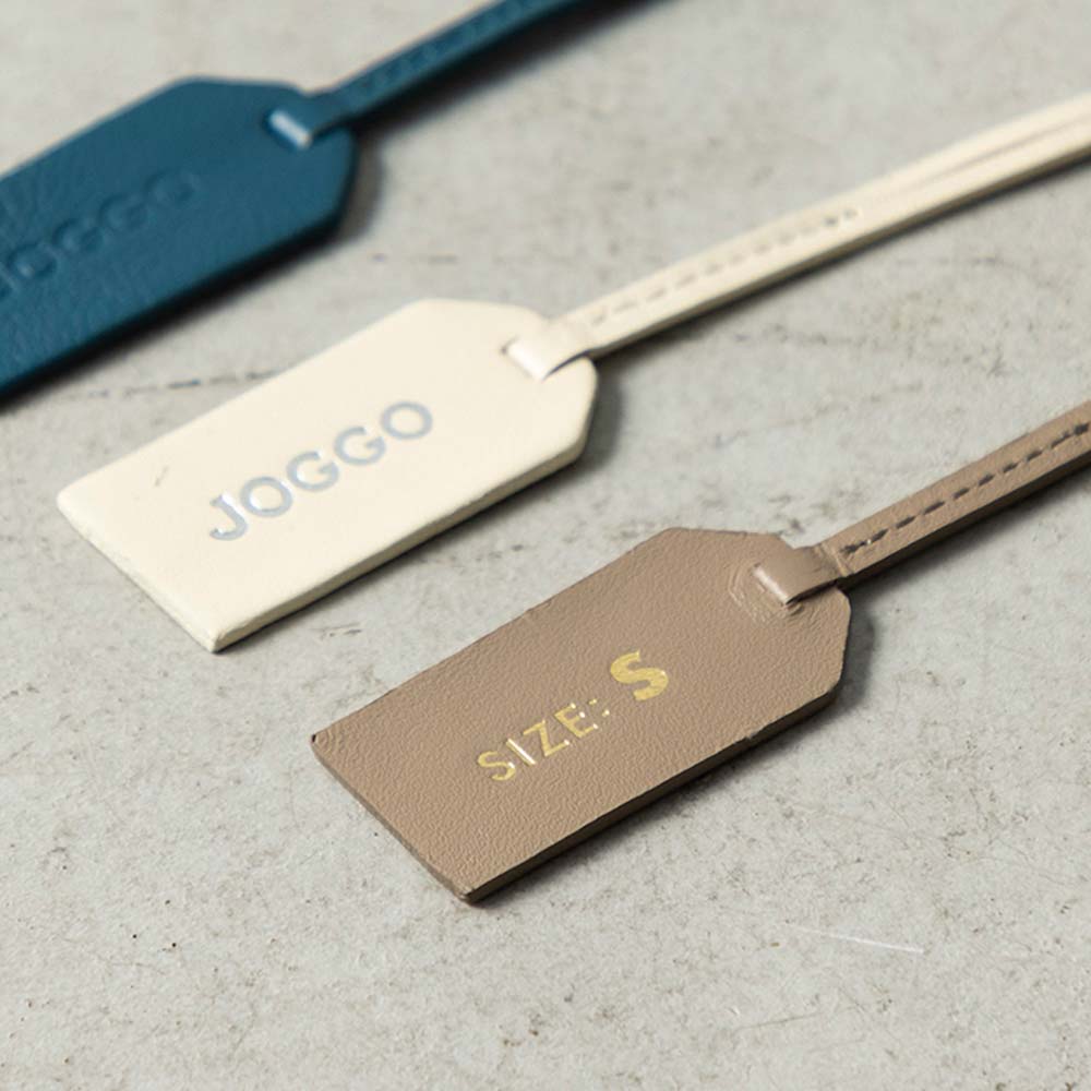 レザートングサンダルＳＳ（21-23cm） - 付属しているブランドタグの片面にＪＯＧＧＯロゴ、もう片面にサイズを刻印しています。タグの色は鼻緒と同じ色になります。※ロゴ刻印をなしにするとサイズのみ刻印された状態になります。