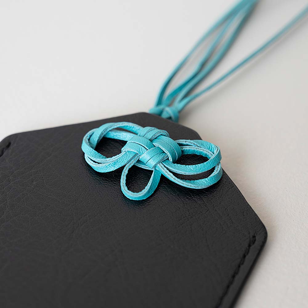 革のお守りケース（ネックレス） - 表側は「口」、裏側は「十」、合わせると「叶」になる二重叶結びという日本古来の結び目になっています。