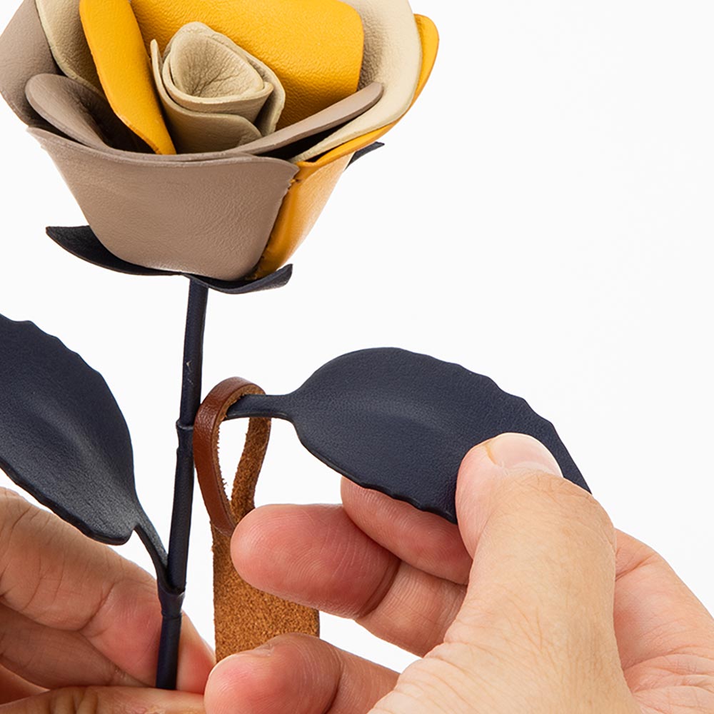 革の一輪花（バラ） - 縁は「コバ塗り」で、革の花びら1枚1枚まで丁寧に仕上げています。葉と茎は革を巻いたワイヤーできているため、お好みで角度を調節できます。※角度をつけすぎたり何度も曲げを繰り返すと、革にシワや割れがおこる恐れがあります。