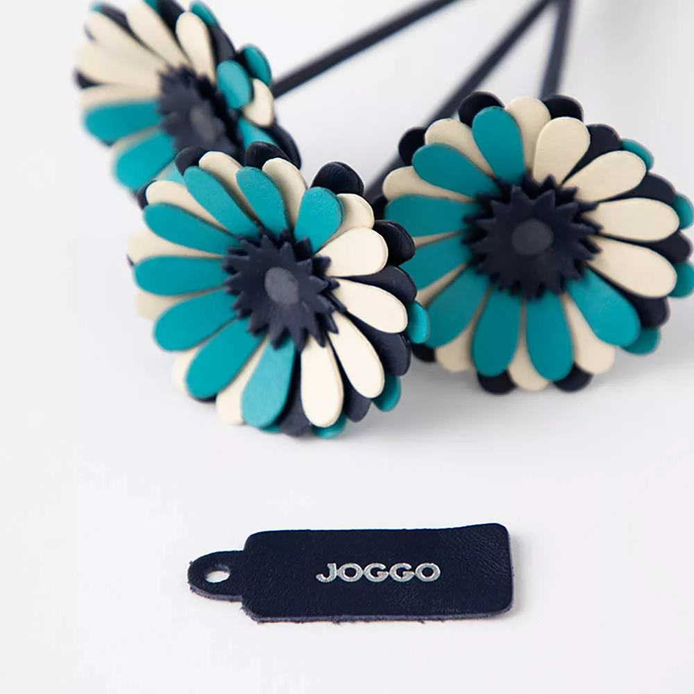 革のブーケ（ガーベラ）３本 - ＪＯＧＧＯのロゴが刻印されたブランドタグが付いています。タグの色でアクセントを加えても素敵です。タグは取り外しも可能です。
